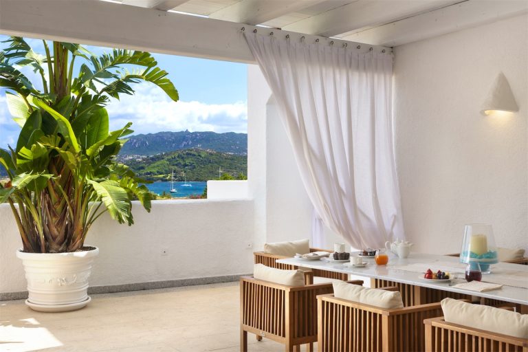 un tavolo apparecchiato per la colazione, su una terrazza con vista sul mare