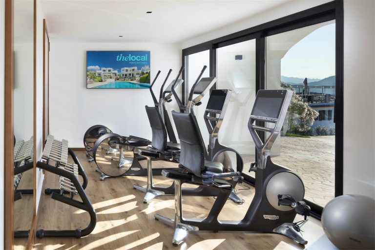 Moderna attrezzatura da fitness nella palestra dell'hotel, con ellittiche, vogatori e bilancieri in metallo cromato