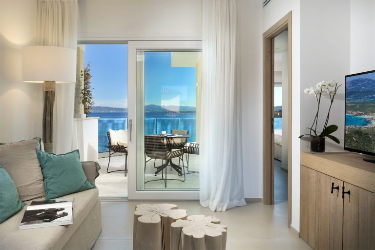 interno di una camera con arredamenti moderni in legno e porta finestra su una veranda con vista sul mare