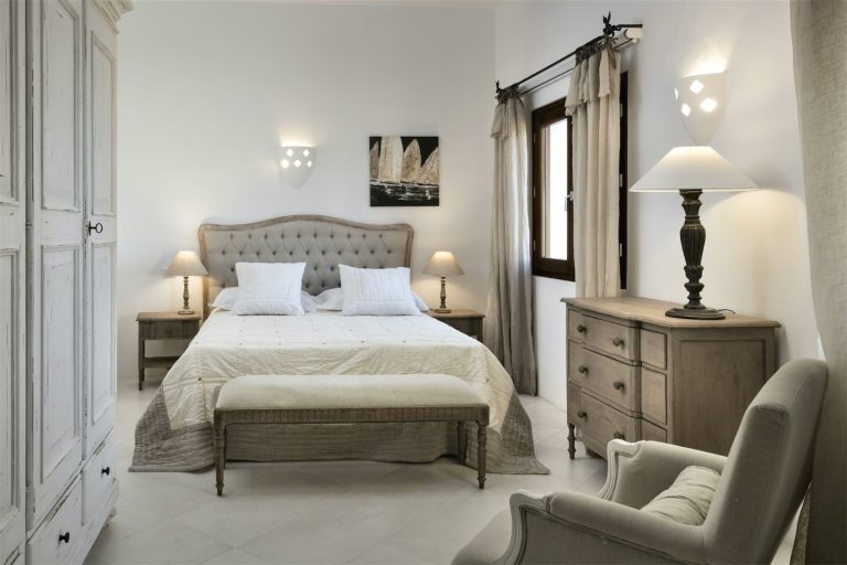 Una stanza dallo stile classico, con letto matrimoniale, comò a cassetti, un armadio e poltrona