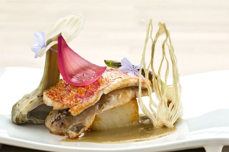 un piatto di pesce ai carciofi, guardino da salsa e fiori colorati
