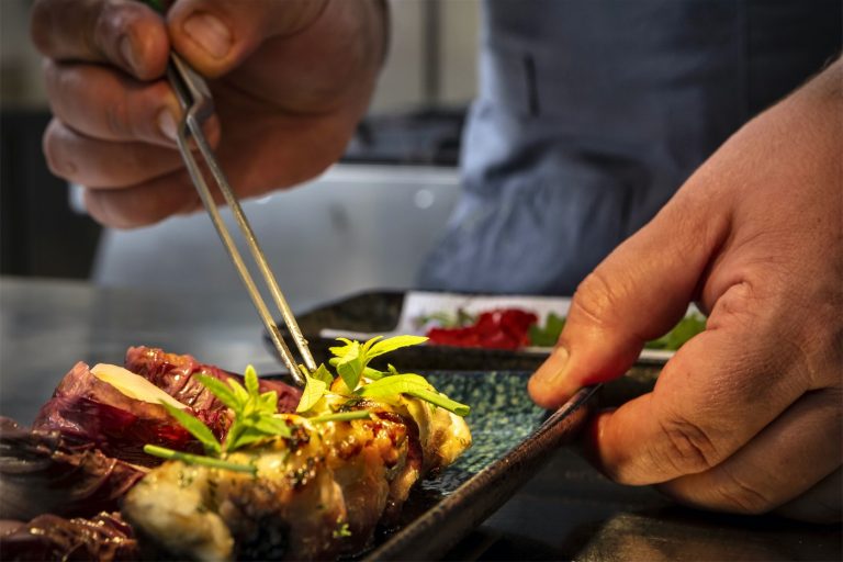 uno chef dà gli ultimi ritocchi ad un piatto di carne grigliata, prima che questo venga servito