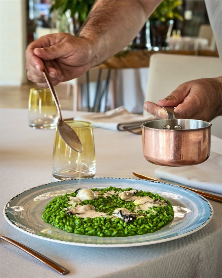 Uno chef finisce di guarnire un piatto di funghi ed altre verdure