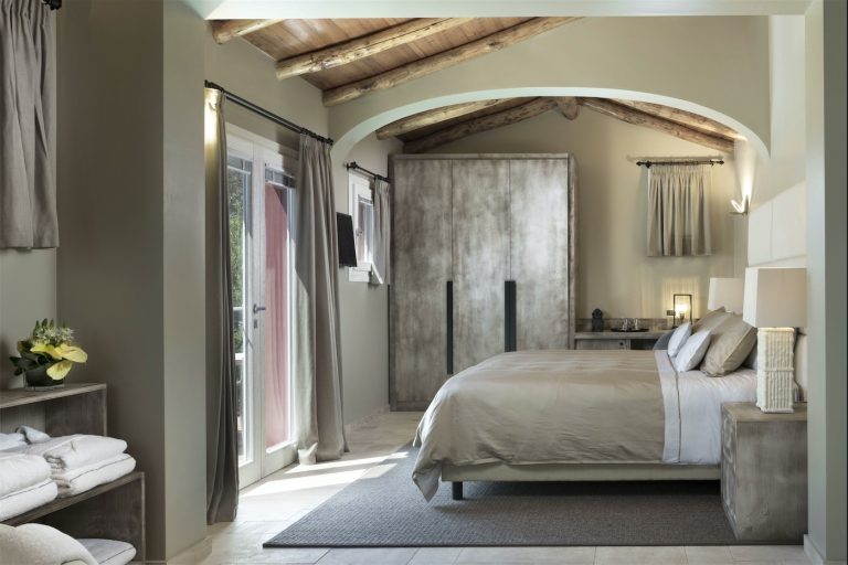 un letto matrimonale di fronte ad una grande vetrata che si affaccia sul giardino