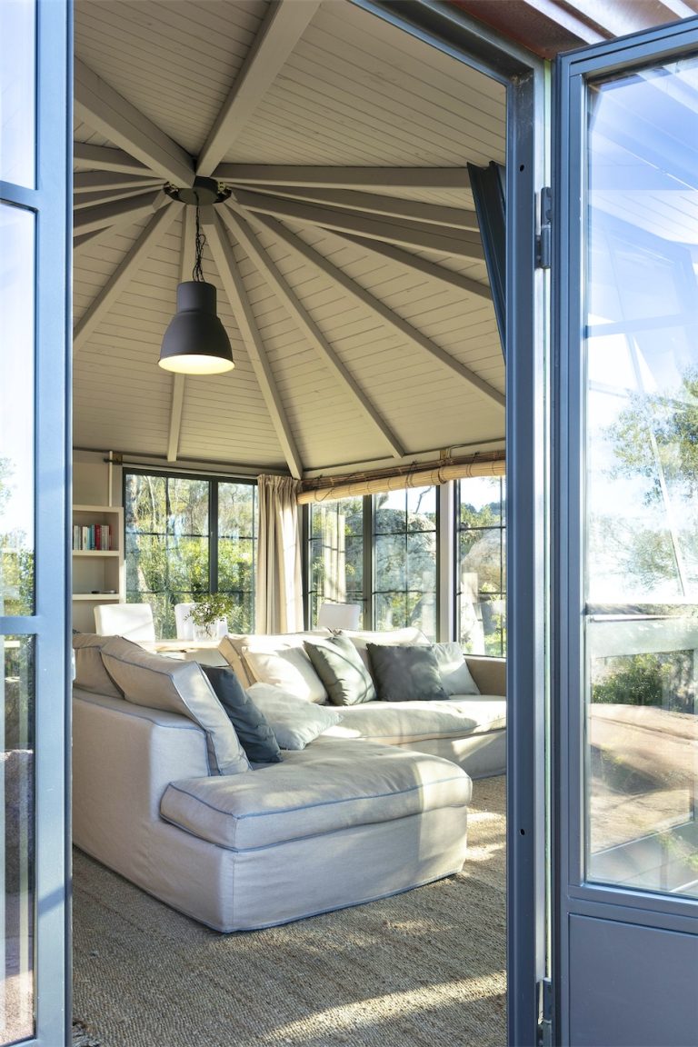 l'interno di un ampio patio con immerso nel verde, con grandi divani, visto dalla porta di ingresso