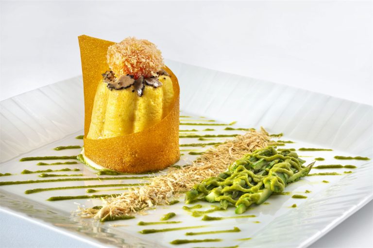 un dessert composto da budino con sfoglia di glassa, crema di pistacchio e granella