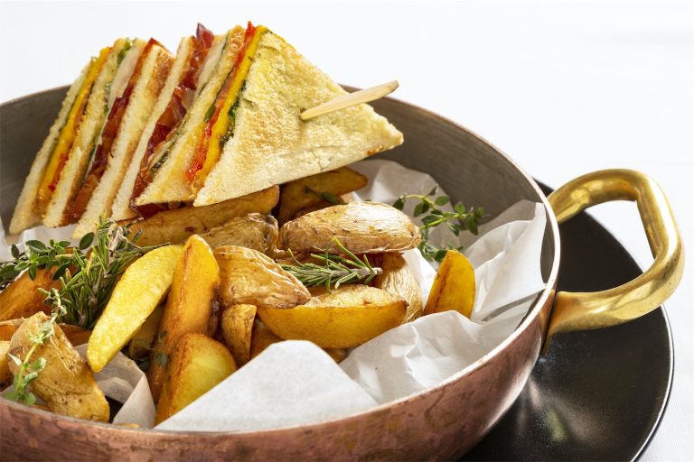 Patate arrosto e tramezzini grigliati serviti in forma di spiedino, in una padella di rame
