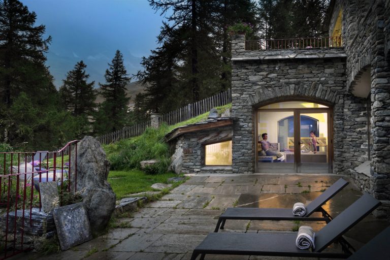 la sauna della SPA vista dal giardino, con pareti facciavista in pietra e grandi vetrate