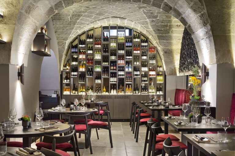due file di tavoli con una parete che ospita nicchie per bottiglie di vino