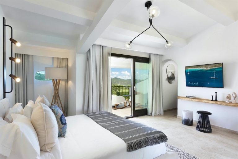 Una grande stanza con letto matrimoniale si affaccia su una veranda privata con vista sul golfo di Cugnana e sul giardino dell'hotel